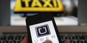 An illustration picture shows the logo of car-sharing service app Uber on a smartphone next to the picture of an official German taxi sign in Frankfurt, September 15, 2014. A Frankfurt high court will hold a hearing on a recent lawsuit brought against Uberpop by Taxi Deutschland on Tuesday.  San Francisco-based Uber, which allows users to summon taxi-like services on their smartphones, offers two main services, Uber, its classic low-cost, limousine pick-up service, and Uberpop, a newer ride-sharing service, which connects private drivers to passengers - an established practice in Germany that nonetheless operates in a legal grey area of rules governing commercial transportation. The company has faced regulatory scrutiny and court injunctions from its early days, even as it has expanded rapidly into roughly 150 cities around the world.   REUTERS/Kai Pfaffenbach (GERMANY - Tags: BUSINESS EMPLOYMENT CRIME LAW TRANSPORT)